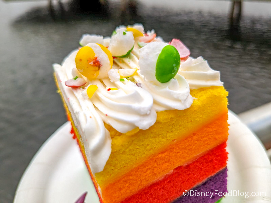 https://www.disneyfoodblog.com/wp-content/uploads/2023/01/2023-wdw-epcot-ep-festival-of-the-arts-fota-figment-inspiration-station-food-booth-rainbow-cake-1.jpg
